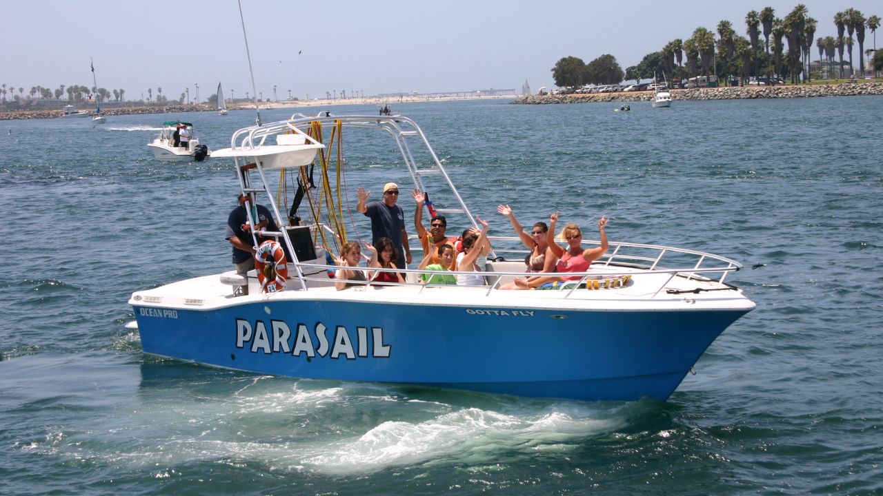 Crew members from Go Parasailing waving as participants get ready on the boat