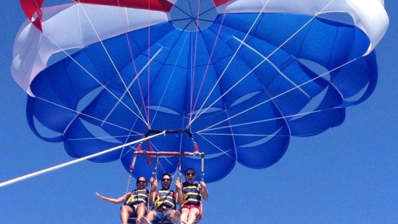 Three people parasailing and enjoying the flight mid air.
