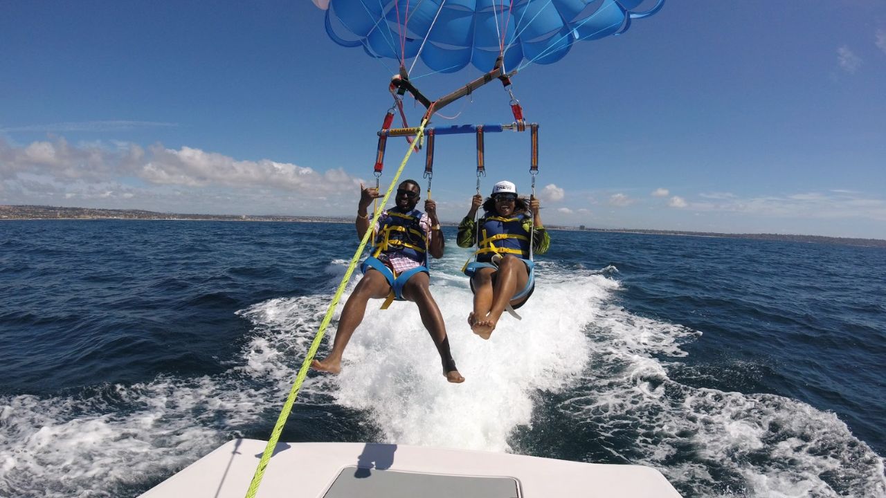 Two people parasailing behind a boat, lifted above ocean waves