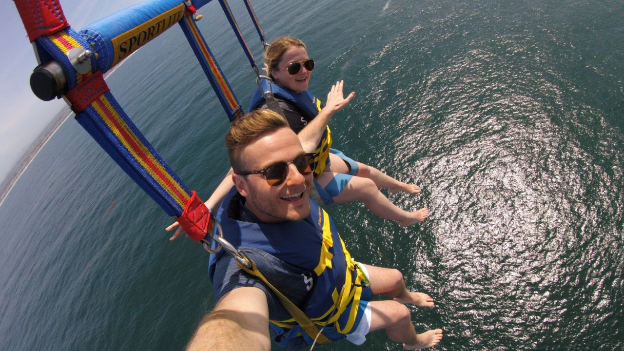 Smiling couple parasailing over sparkling ocean water