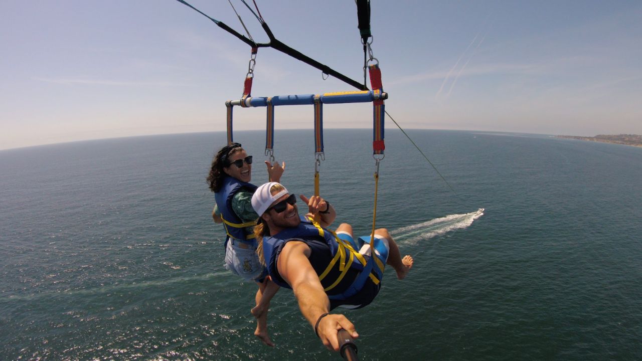 Couple parasailing above the ocean taking a selfie.