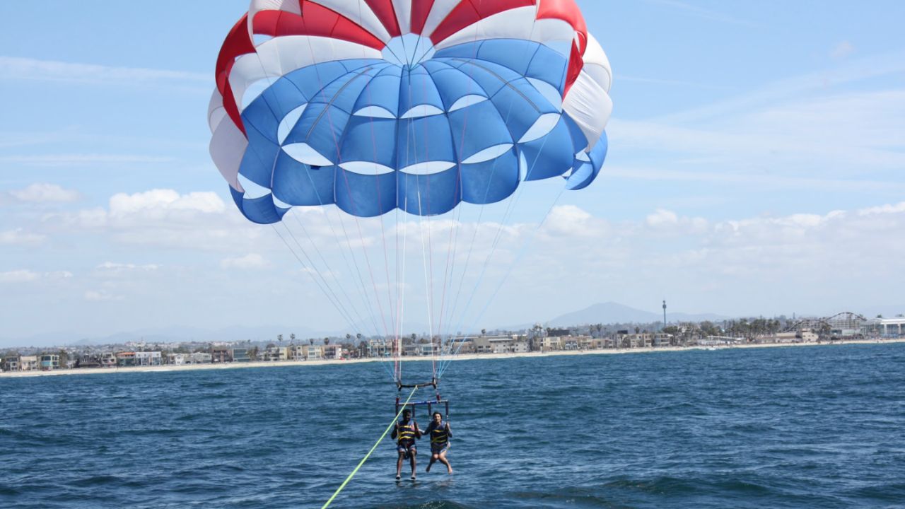 Two people parasailing near shore operated by San Diego Parasail Adventures.
