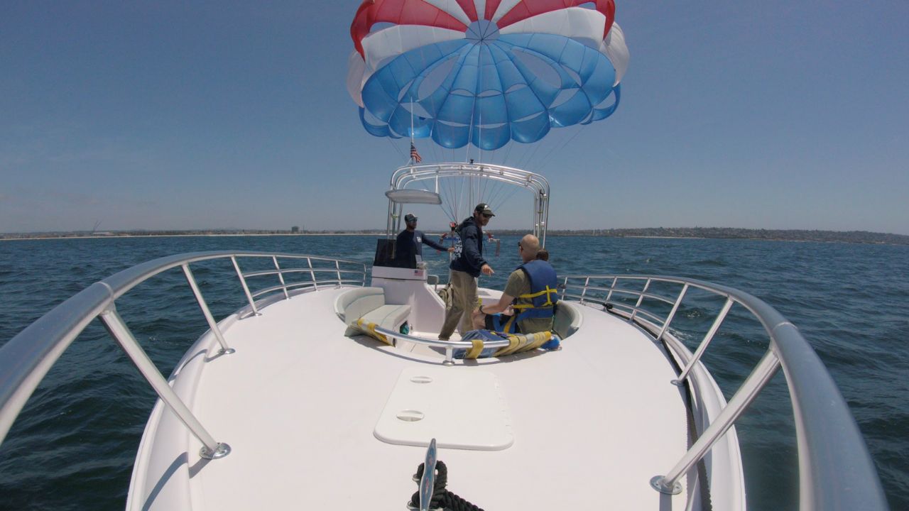 Parasailing crew preparing riders on boat before takeoff over ocean