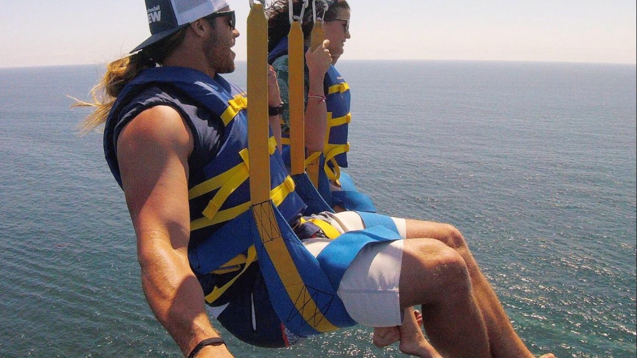 Couple enjoying tandem parasailing ride over calm coastal waters 