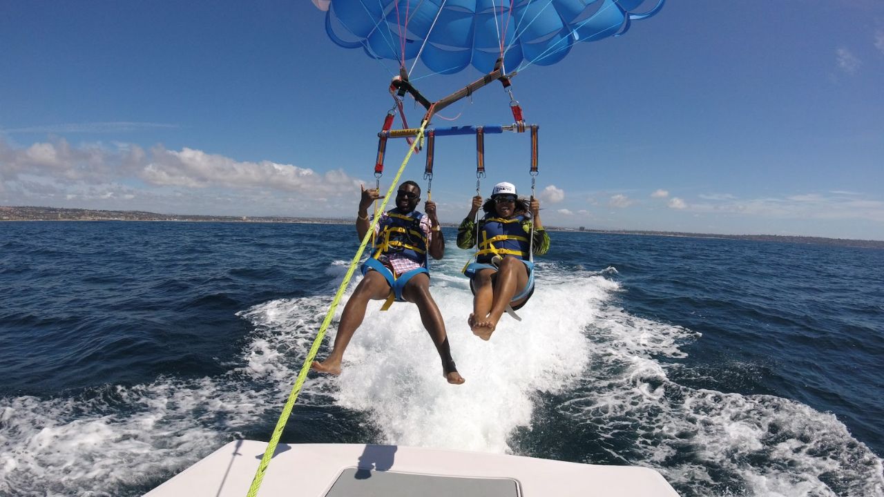 Couple parasailing behind a speedboat on a sunny San Diego ocean tour