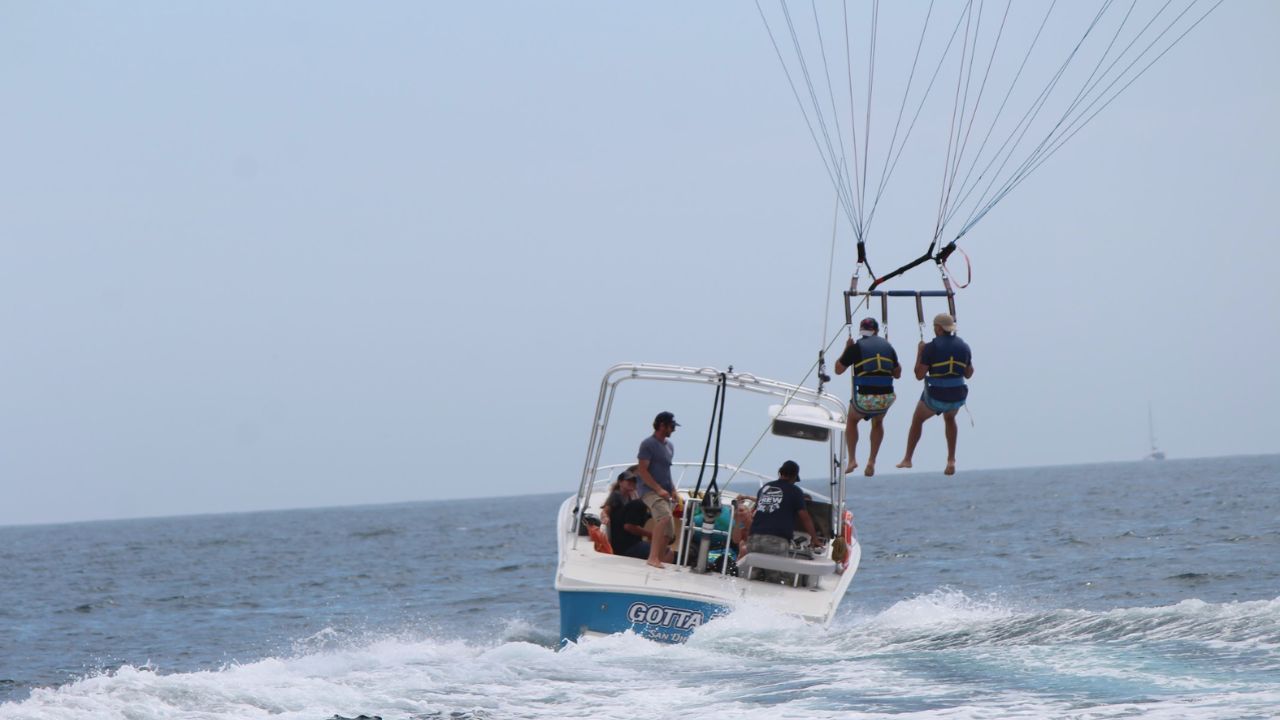  Parasailing takeoff from boat with two riders flying above ocean 