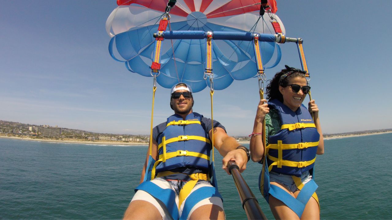 Couple enjoying tandem parasailing with ocean and coastline views in San Diego