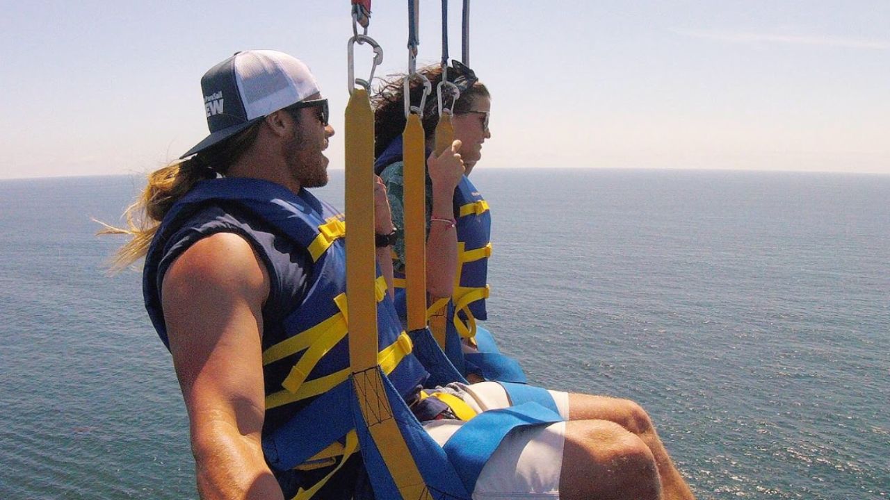 Two guests soar high above the water with stunning coastal views.