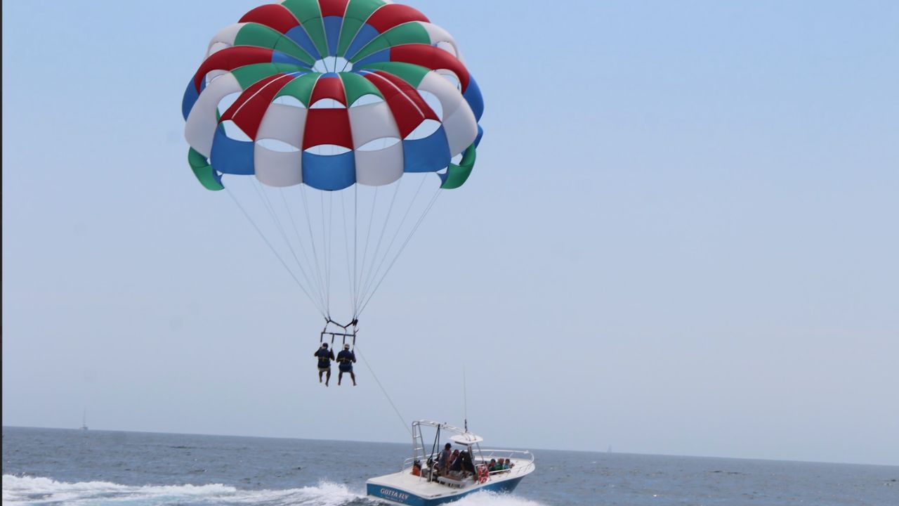 Colorful parasail soaring above the ocean as a speedboat pulls riders across the water on a sunny day