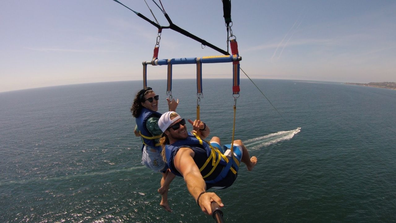 Two parasailers capturing a selfie while soaring above the ocean. 