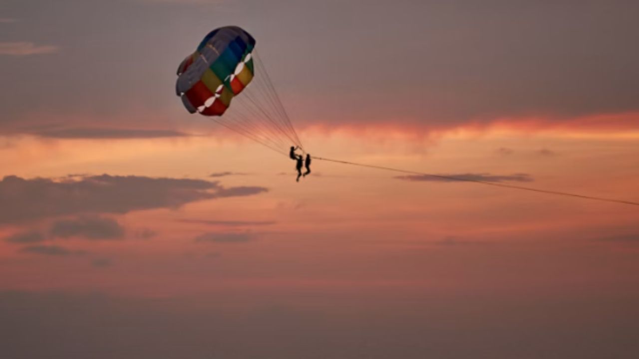 Parasailing over the ocean at sunset.